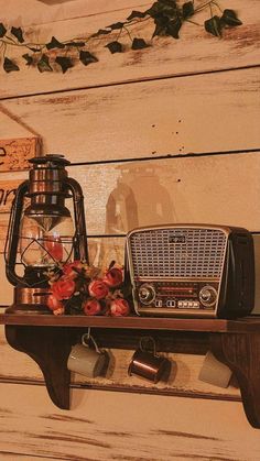 an old fashioned radio sitting on top of a shelf next to a lamp and flowers