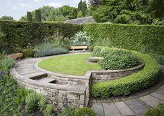 a circular garden area with stone steps and benches in the center, surrounded by greenery