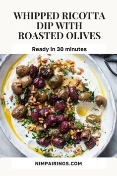 a white plate topped with roasted olives and other food on top of a table