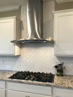 a stove top oven sitting inside of a kitchen next to white cabinets and counter tops