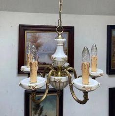 a chandelier hanging from the ceiling in a room with pictures on the wall