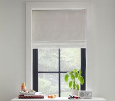 a white table with a potted plant on it next to a window