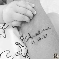 a close up of a person holding a baby's arm with a tattoo on it