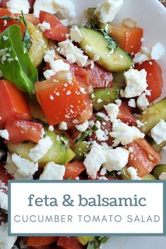 a white plate topped with cucumber, tomato and feta salad on top of a wooden table