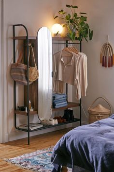 a bedroom with a bed, mirror and hanging clothes