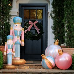 an assortment of christmas decorations on steps outside a door with wreath and nutcrackers