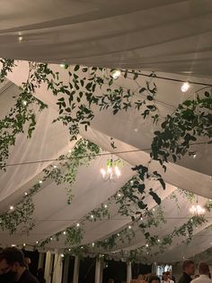 the ceiling is covered with white drapes and greenery hanging from it's sides