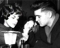 a man and woman sitting at a table in front of a blender with something in it