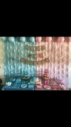 a table topped with lots of cake and desserts next to a wall covered in balloons