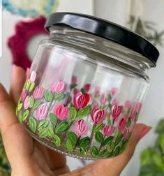 a hand holding a jar with flowers painted on it