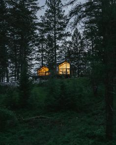 a small cabin in the woods lit up at night with lights coming from it's windows