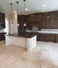 a large kitchen with wooden cabinets and marble counter tops, along with an island in the middle