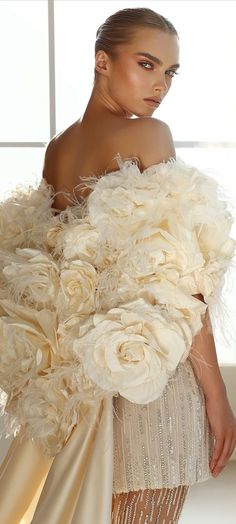 a woman in a white dress with flowers on her shoulders and an over - sized shawl