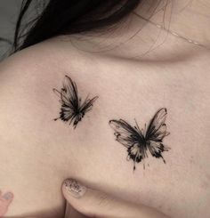 two butterfly tattoos on the back of a woman's shoulder and chest, both with black ink