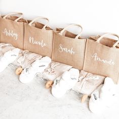 several bags with names are lined up on a counter top next to some baby booties