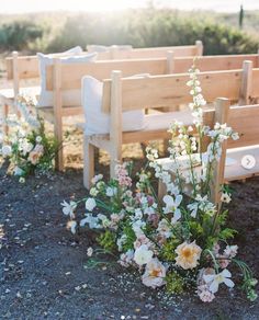 flowers and greenery are placed in front of the pews at an outdoor wedding ceremony