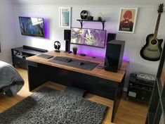 a computer desk with a guitar and speakers on it in a room filled with furniture