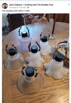 five glass vases sitting on top of a wooden table next to a candle holder