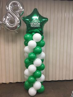 a balloon column with white and green balloons in the shape of a star is shown