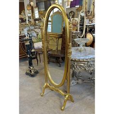 a large gold colored mirror sitting on top of a wooden floor next to tables and chairs