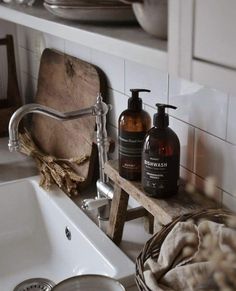 two bottles of hand soap sit on a shelf next to a sink