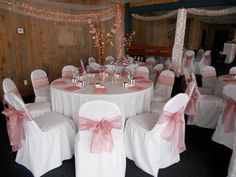 the banquet room is set up with white linens and pink bows