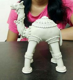 a woman sitting at a table next to a small white horse figurine on top of a wooden table