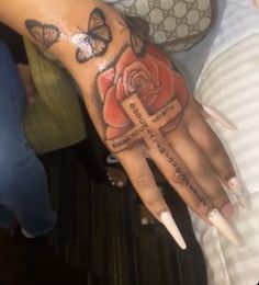 a woman's hand with a cross and roses tattoo on it, surrounded by butterflies