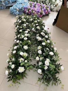 white and purple flowers are arranged in the shape of an x on display at a flower shop