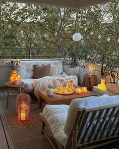 an outdoor living area with wicker furniture and lit candles on the table, surrounded by trees