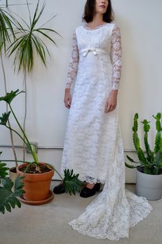 a woman in a white dress standing next to plants