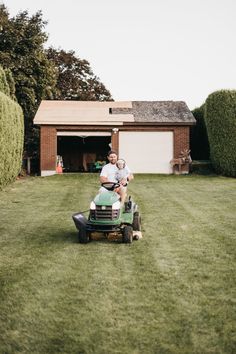 a man riding on the back of a green lawn mower