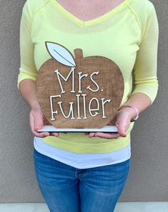 a woman holding up a wooden sign that says mrs fuller