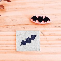 a wooden table topped with a bat shaped cookie next to a rubber stamp on top of a piece of paper