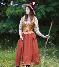 a woman in a dress and hat holding a stick