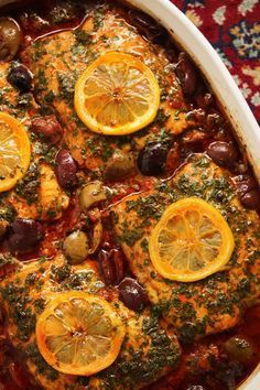 a casserole dish with lemons, olives and meat