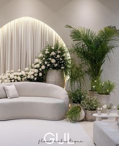 a white couch sitting next to two potted plants on top of a floor covered in flowers