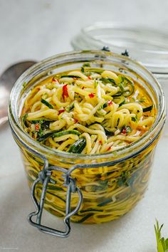 a glass jar filled with noodles and vegetables