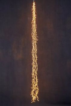 a long string of lights hanging from the side of a building in front of a black wall