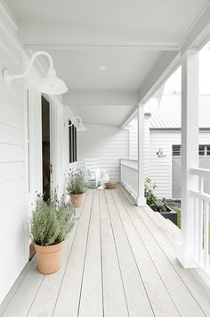 a white porch with potted plants on it