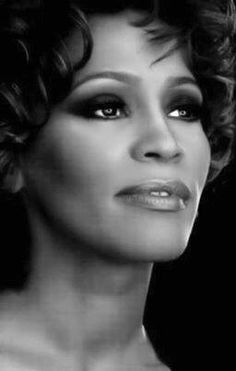 a black and white photo of a woman with curly hair looking at the camera while wearing an evening dress