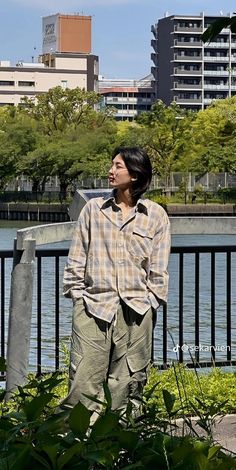 a man standing on the edge of a bridge next to a body of water with buildings in the background