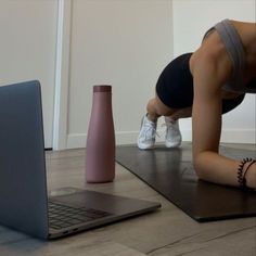 a woman doing push ups in front of a laptop