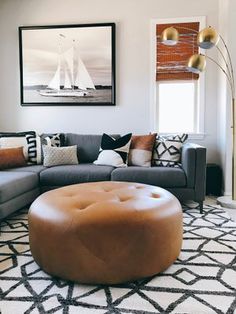 a living room filled with furniture and a large brown leather ottoman sitting on top of a rug