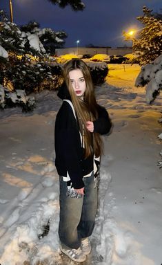 a girl standing in the snow with her hair blowing back and looking at the camera