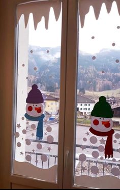 two frosted windows with snowmen on them and mountains in the backround