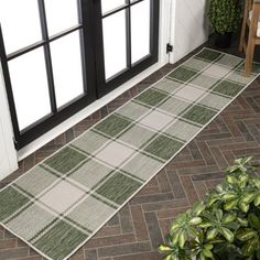 a green and white rug sitting on top of a wooden floor next to a door