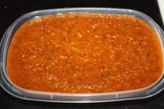 a plastic container filled with red sauce on top of a counter