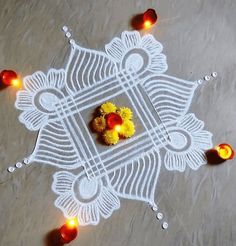 a white doily with yellow flowers and candles on the ground next to it,