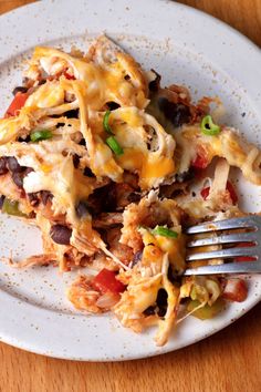 a white plate topped with lasagna covered in cheese and toppings next to a fork